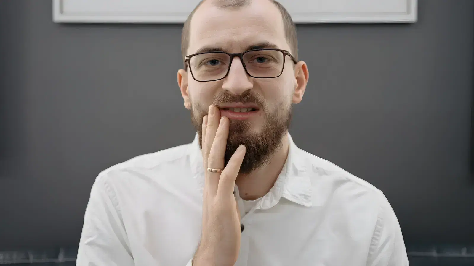 A man pressing a hand to his jaw, working out whether his tooth pain needs same-day care