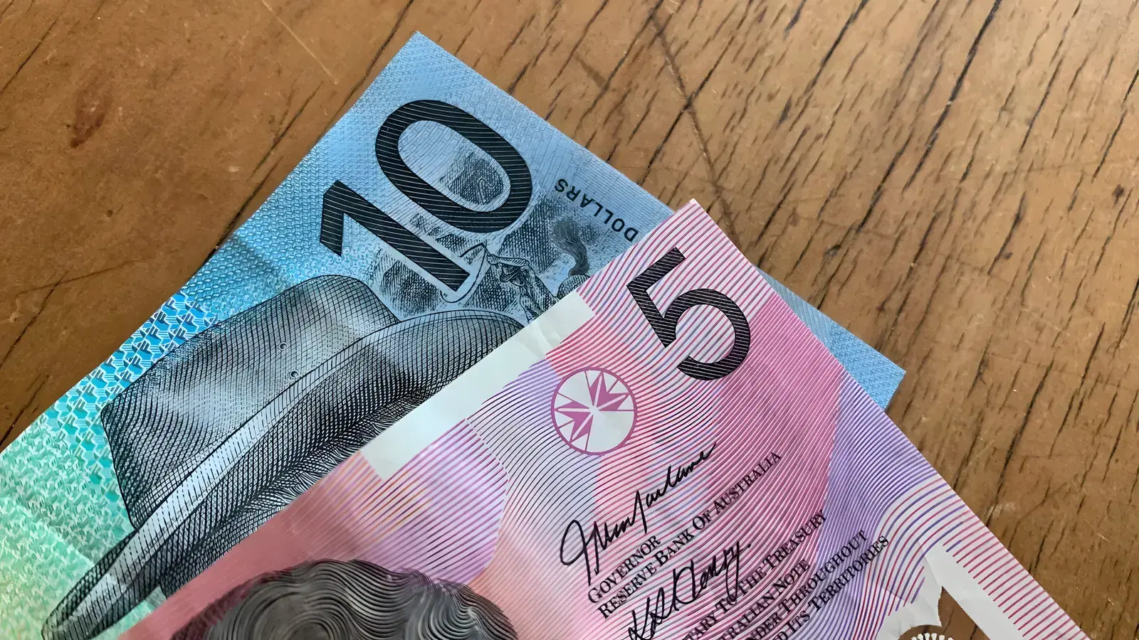 An Australian ten dollar note and five dollar note lying on a wooden tabletop